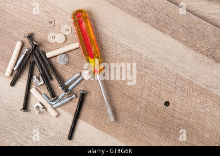 High Angle Still Life View of Yellow Handled Flathead Screwdriver, Screws and Various Pieces of Hardware Beside Small Hole Drill Stock Photo