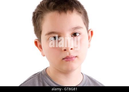Head and Shoulders Close Up Portrait of Young Boy in Gray T-Shirt Staring at Camera with Blank Expression in Studio with White B Stock Photo