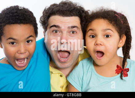 Close up Surprised Dad with Two Cute Kids Looking at the Camera with Mouth Wide Open Against White Background, Emphasizing Multi Stock Photo