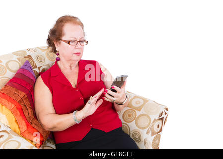 Senior Woman Sitting on a Couch While Reading Messages on her Mobile Phone, Isolated on White. Stock Photo