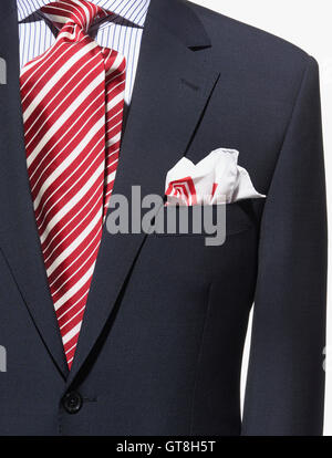 Detail of a dark blue suit jacket with red and white striped necktie and handkerchief and striped shirt Stock Photo