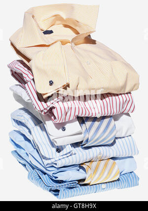 Stack of multi coloured shirts with ties on white background Stock Photo