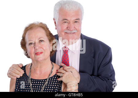 Smiling husband in blue suit with red tie standing behind his contented wife and holding her hand over white background Stock Photo