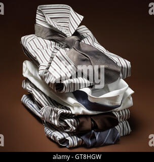 Stack of men's, striped dress shirts with ties on brown background Stock Photo