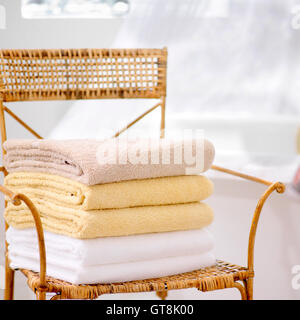 Stack of Fresh Towels on Wicker Chair in Bathroom Stock Photo