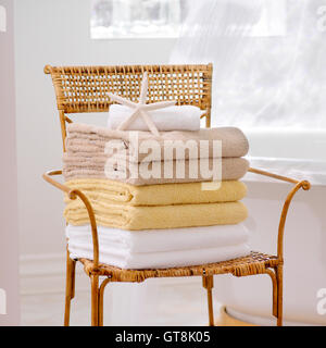 Stack of Fresh Towels and Starfish on Wicker Chair in Bathroom Stock Photo