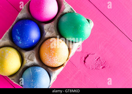 Six colorful hand decorated Easter eggs dyed with different colored pigments and displayed in a cardboard carton on an exotic ma Stock Photo