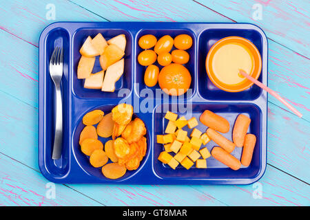 Assorted fresh and dried fruit cut into small pieces and juice in orange colors on blue plastic tray with stainless steel fork o Stock Photo
