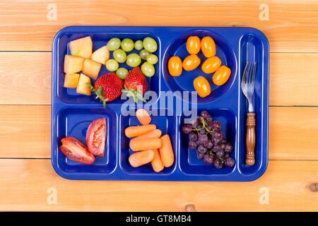 Delicious tangy and sweet fruit sampler of melon, grapes, tomatoes, carrots and grapes in lunch tray with fork Stock Photo