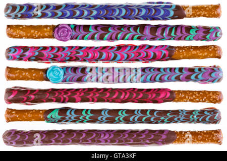 Row of seven colorfully decorated chocolate covered pretzel sticks on a white background Stock Photo