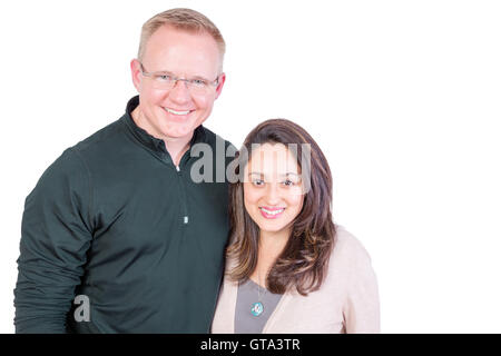 Happy smiling multiracial couple standing arm in arm looking at the camera with warm beaming friendly smiles isolated on white w Stock Photo