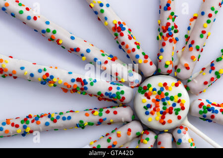 Top down close up on wheel of straight shaped pretzels coated in white chocolate and colorful candy sprinkles Stock Photo