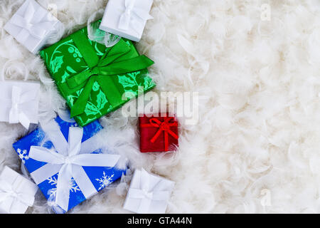 Various little wrapped boxes in blue, green, red and white with copy space surrounded by feathers for expensive gift concept Stock Photo