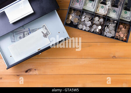 Top down view on separate cash drawer stocked with coins and American dollars beside open register with key and large denominati Stock Photo