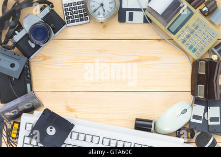 Background with old electronics placed in a circle on a wooden table with such items as calculators and floppy disks Stock Photo