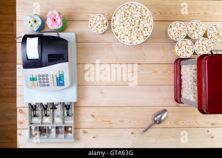 Bowls of fresh popcorn alongside a till or cash register with an open drawer displaying American dollar banknotes and coins and Stock Photo