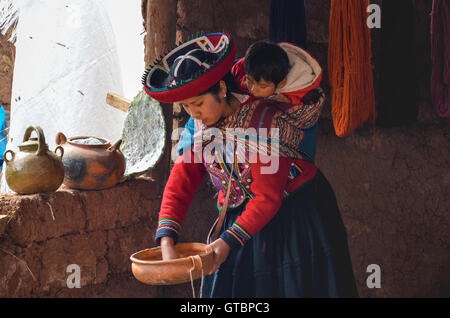 Native woman dressed in traditional colourful clothing explaining the dyeing threads and weaving Stock Photo