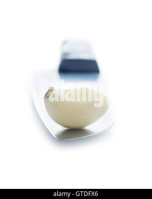 Peeled garlic clove on the knife. Isolated on white background. Stock Photo