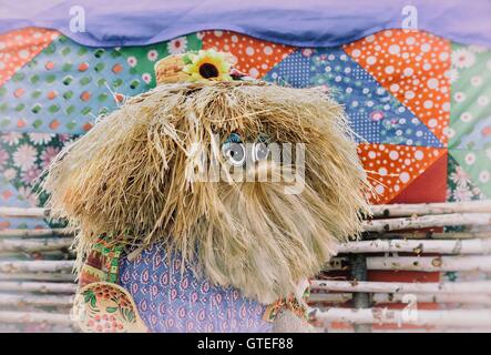 Fun doll in the form of a man with long hair and a beard, a small hat on the background of the fence.. Stock Photo