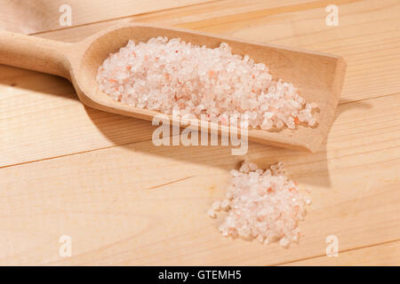 wooden spoon full of stone salt on a table Stock Photo