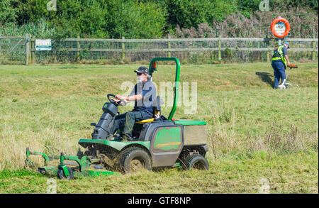 Man cutting grass in a park with a ride on lawnmower. Stock Photo