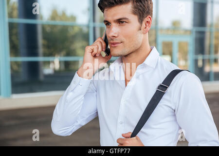 Young handsome pensive businessman talking on the phone outdoors Stock Photo