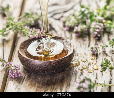 Herbal honey pouring into the wooden bowl. Bowl is on old wooden table surrounded with lavender flowers. Stock Photo