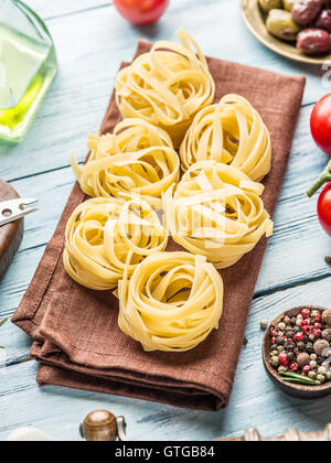 Pasta ingredients. Cherry-tomatoes, spaghetti pasta, rosemary and spices on the wooden table. Stock Photo
