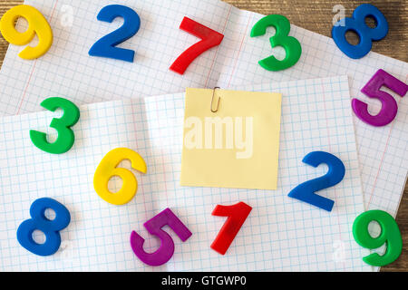 Squared exercise book with colored numbers and blank sticky note Stock Photo