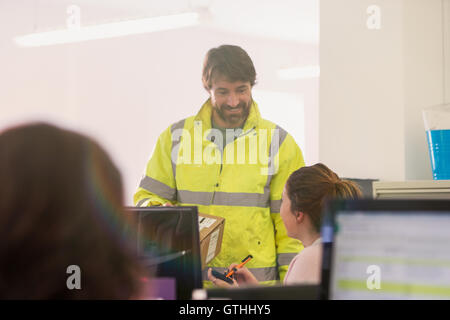 Deliveryman delivering package to businesswoman in office Stock Photo