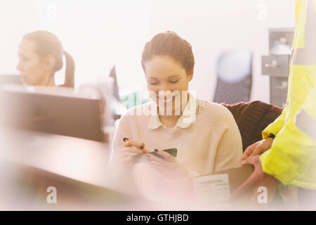 Smiling businesswoman signing for package delivery Stock Photo