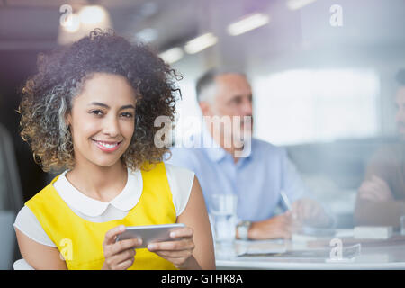 Portrait smiling businesswoman texting with cell phone in meeting Stock Photo