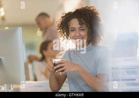 Portrait smiling businesswoman drinking coffee in office Stock Photo