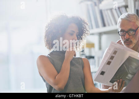 Designers discussing paperwork in meeting Stock Photo