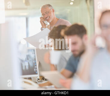 Architect with blueprints talking on telephone in office Stock Photo