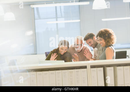 Business people waving video conferencing at laptop in office Stock Photo