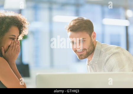 Laughing businesswoman and businessman working at computer in office Stock Photo