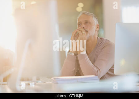 Focused businessman working at computer in sunny office Stock Photo