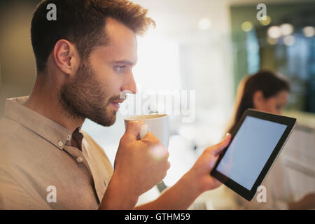 Businessman drinking coffee using digital tablet in office Stock Photo