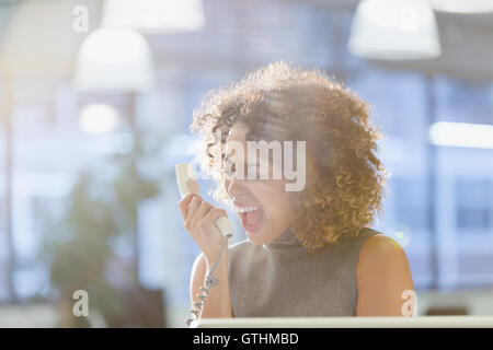 Businesswoman screaming into telephone Stock Photo