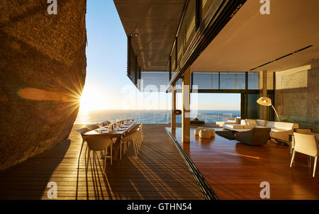 Sun setting behind modern luxury patio dining table with ocean view Stock Photo
