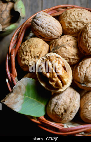 Walnut in basket and whole walnuts on rustic old wood Stock Photo