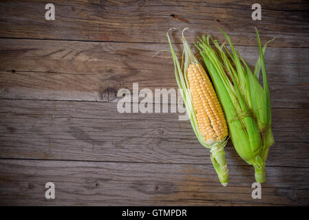 cob of fresh corn with leaves on a wooden table Stock Photo