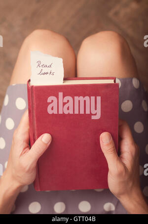 Hand holding a book with note of paper with the message read books on it Stock Photo
