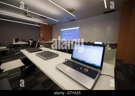empty it classroom with program code on projector screen and modern laptop computers on table Stock Photo
