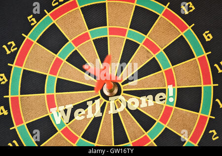 Text Well Done written on the circular target with a plastic feather in the center Stock Photo