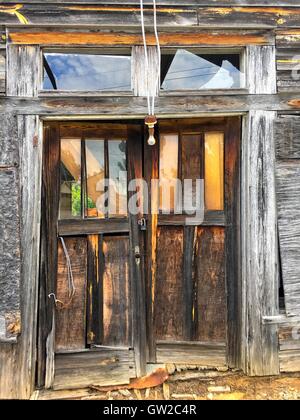 Entry doors to an old abandoned wooden shed.  A light is hanging down and the glass in the doubles is broken. Stock Photo
