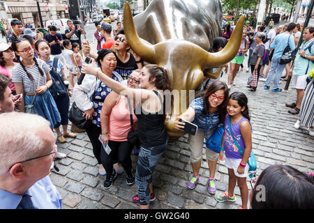 New York City,NY NYC,Lower Manhattan,Financial District,Bowling Green,public park,Charging Bull,Wall Street Bull,bronze,sculpture,Asian Asians ethnic Stock Photo