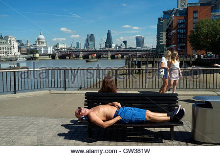 Man laying on bench sunbathing in front of Port of Liverpool Stock ...