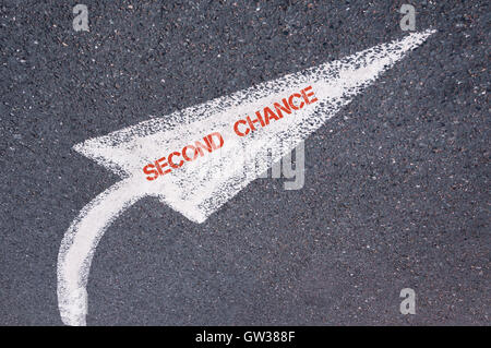 Directional white painted arrow with words SECOND CHANCE over road surface, concept image Stock Photo